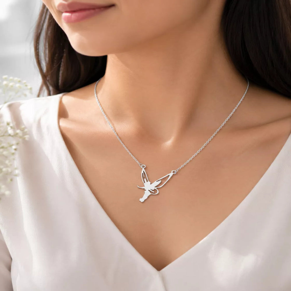  woman wearing a delicate silver necklace with a winged fairy pendant, styled with a white V-neck top.