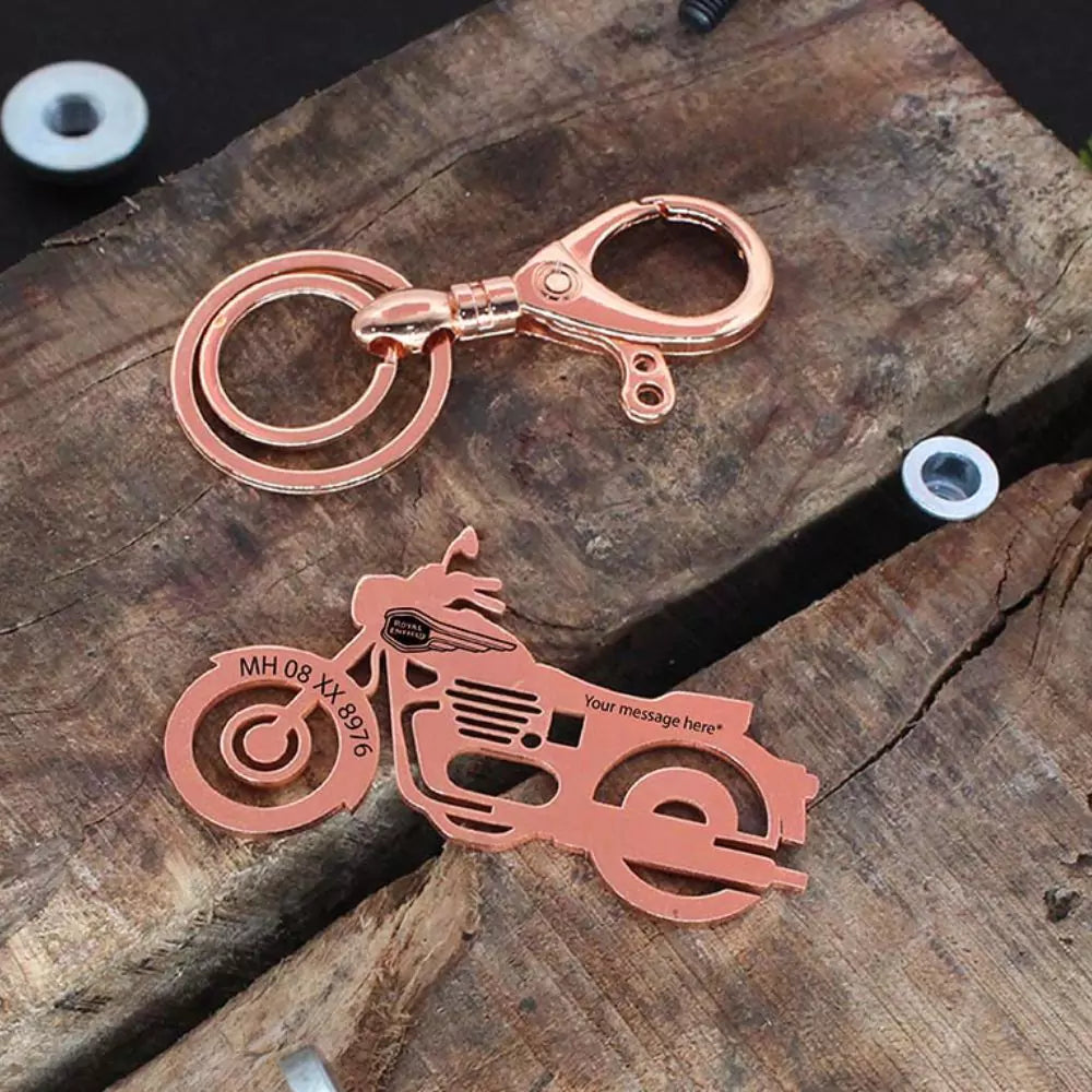 Rose gold motorcycle keychain on a wooden surface